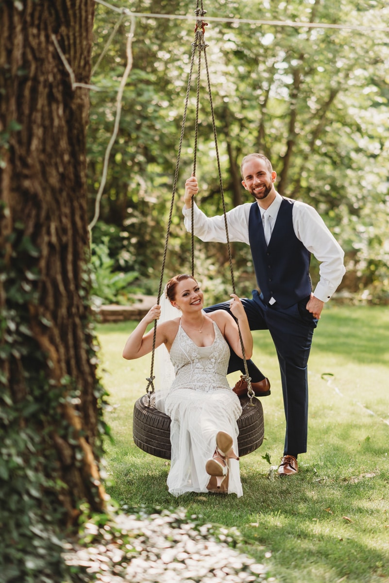 Groom pushes bride on tire swing