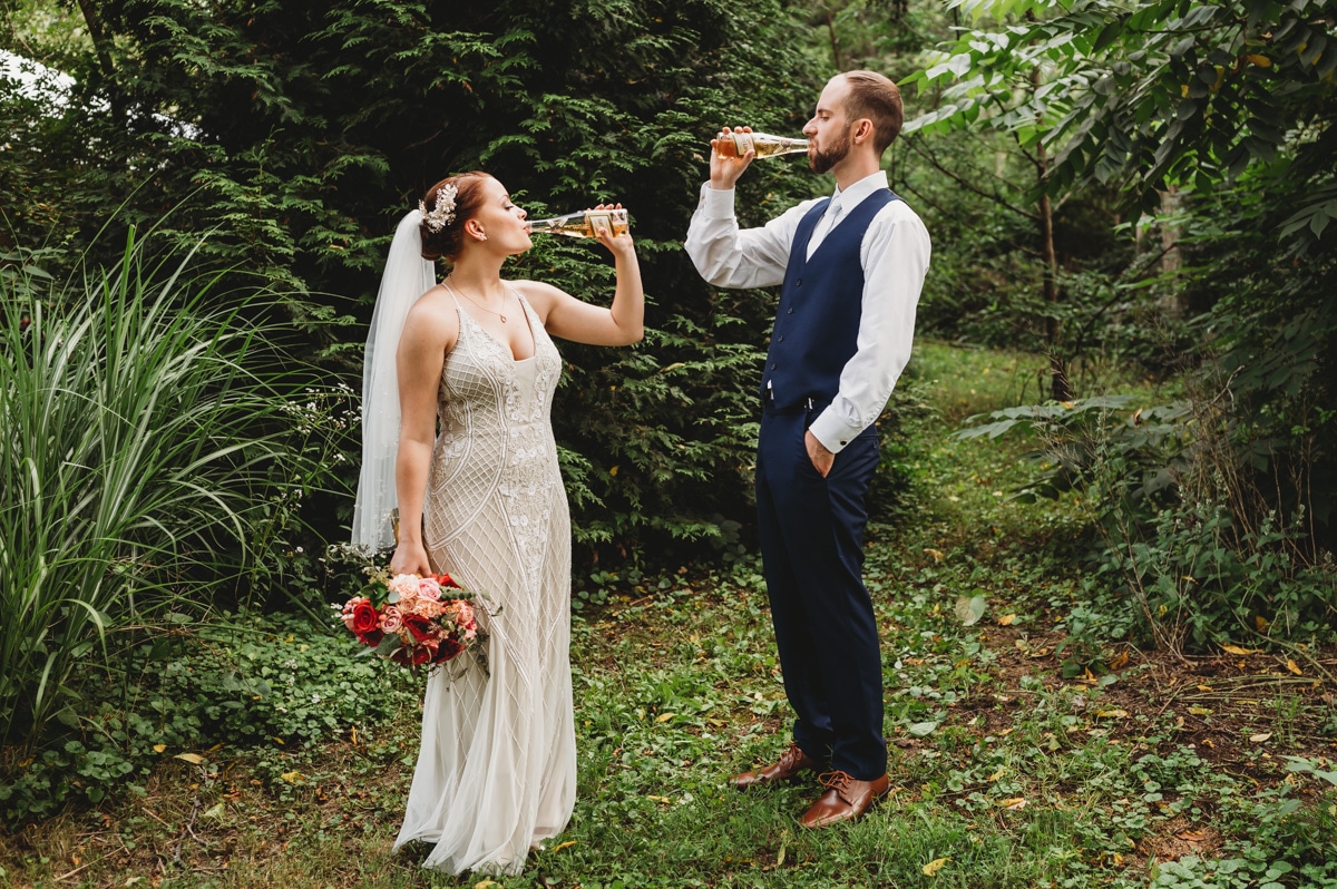Bride and groom drinking beer in field